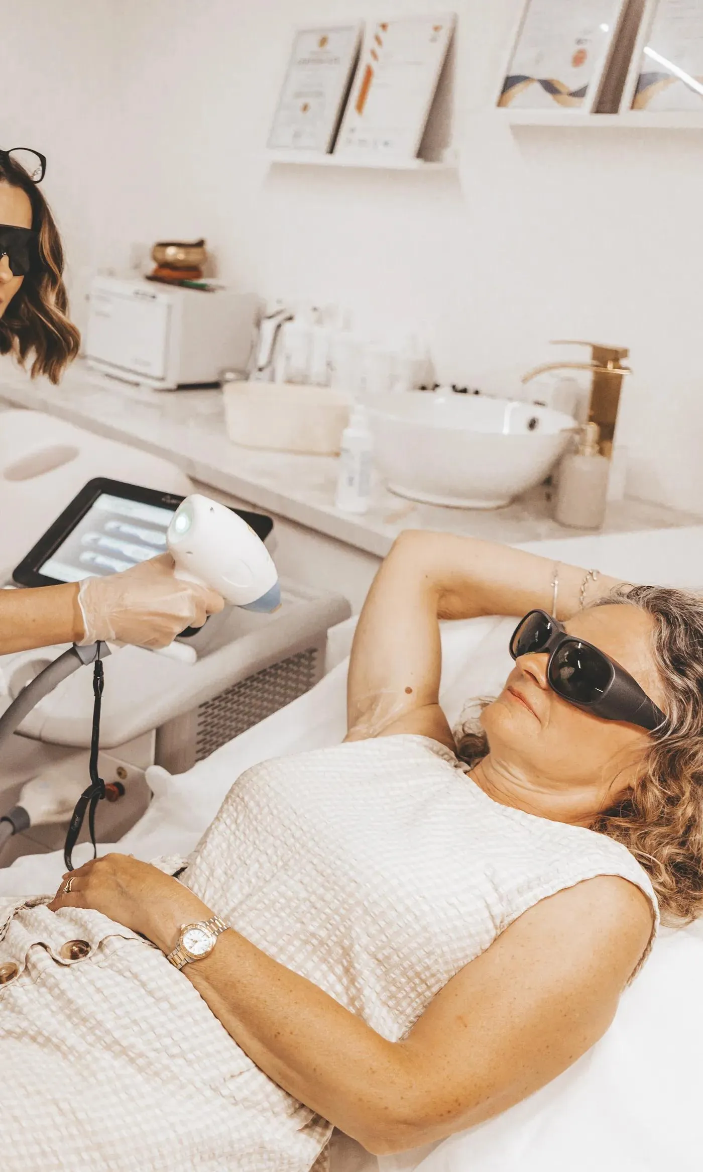 Sarah demonstrating laser hair removal on a client while two students observe in safety eyewear